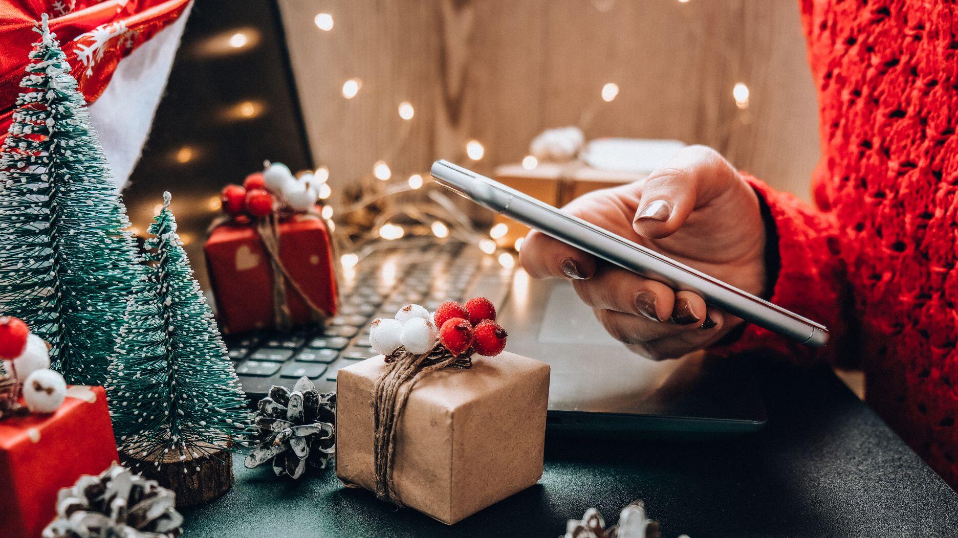 The first predictions about the 2024 holiday season have begun rolling in, with Deloitte forecasting 2 to 3 percent retail sales growth and a “solid” holiday overall, and Adobe Analytics touting the importance of mobile shopping and generative AI. Stock image of hand holding phone by keyboard
