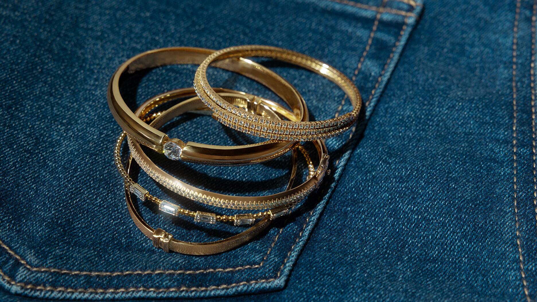 A selection of gold bracelets and bangles from Signet Jewelers-owned banner Zales. Signet posted Q1 sales of $1.54 billion, up 2 percent year-over-year. Gold and diamond bangles on a pair of jeans