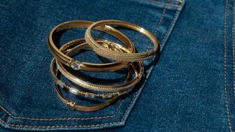 Gold and diamond bangles on a pair of jeans